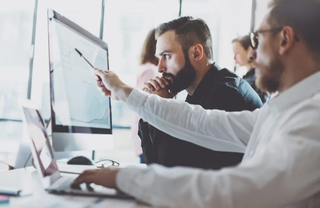 Digital ID and cyber security: Two men working in finance look at a computer screen